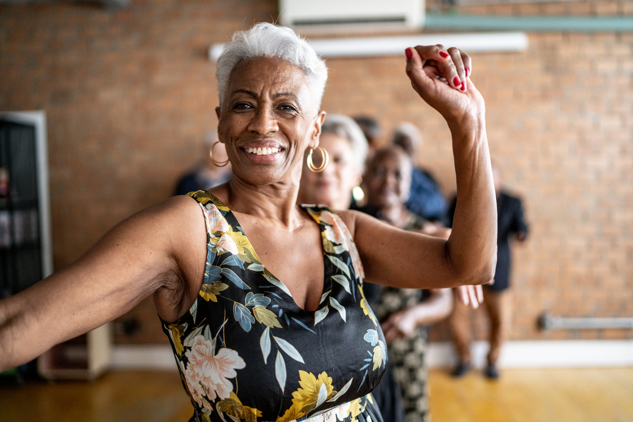 Older Black woman dancing at the front of a Conga line