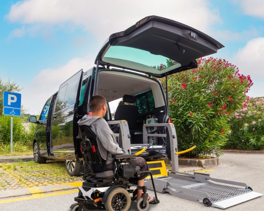Man prepares to board accessible transport vehicle in his motorized wheelchair