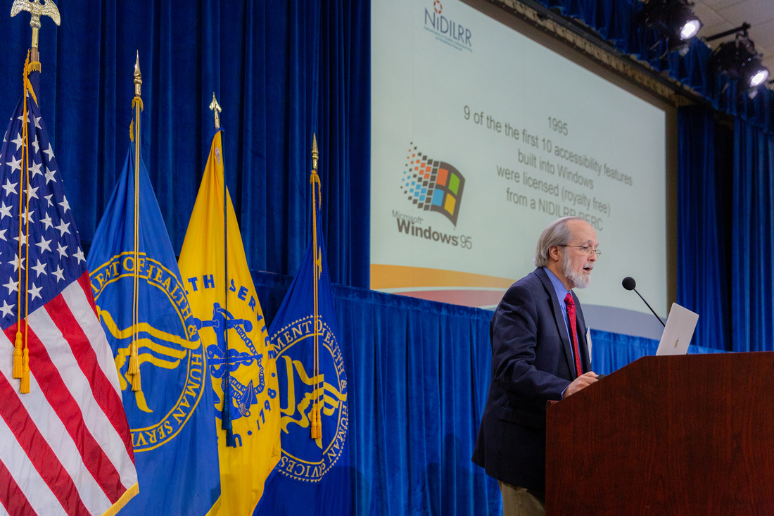 Dr. Vanderheiden presenting in front of a screen with a Windows 95 logo