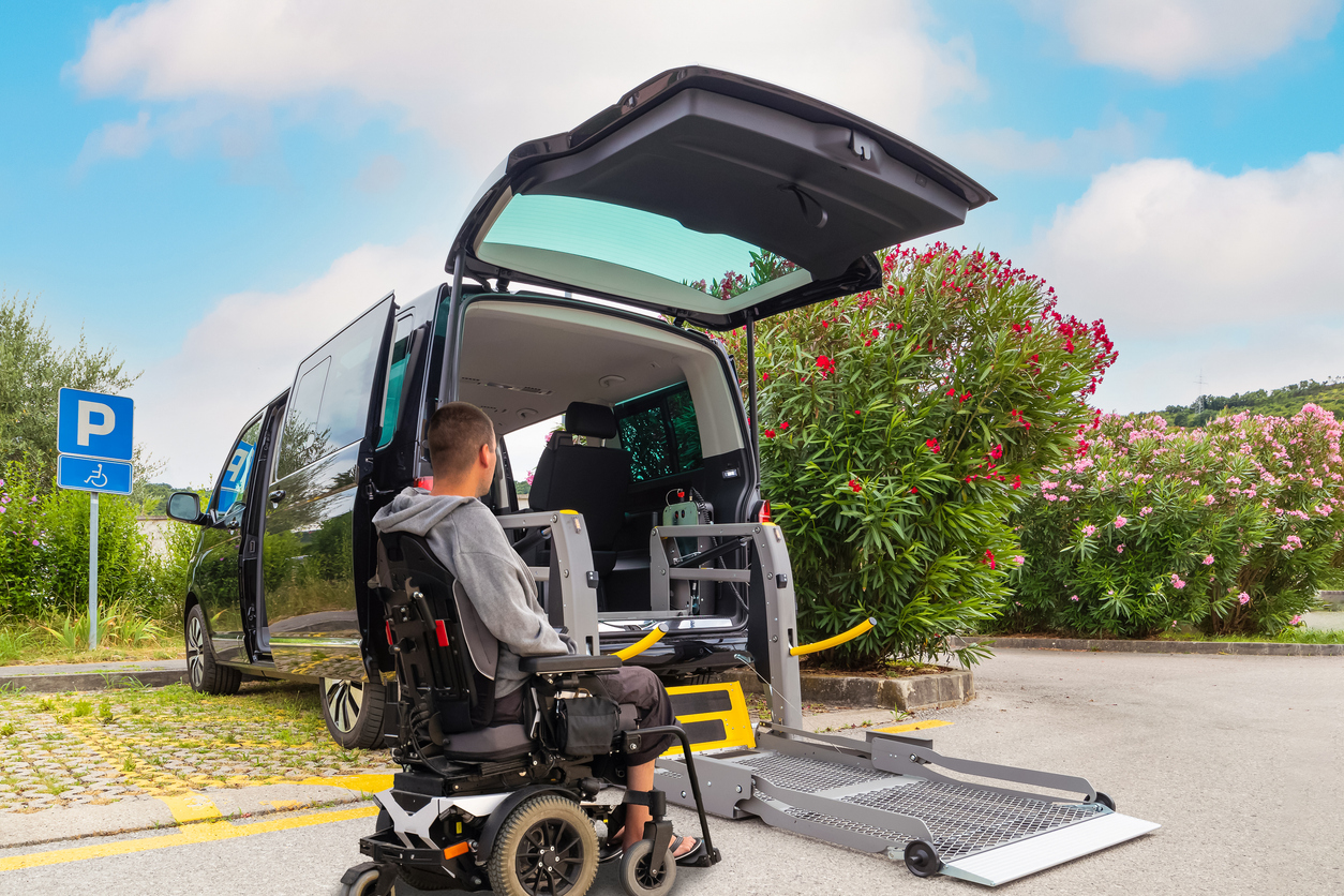 Man prepares to board accessible transport vehicle in his motorized wheelchair