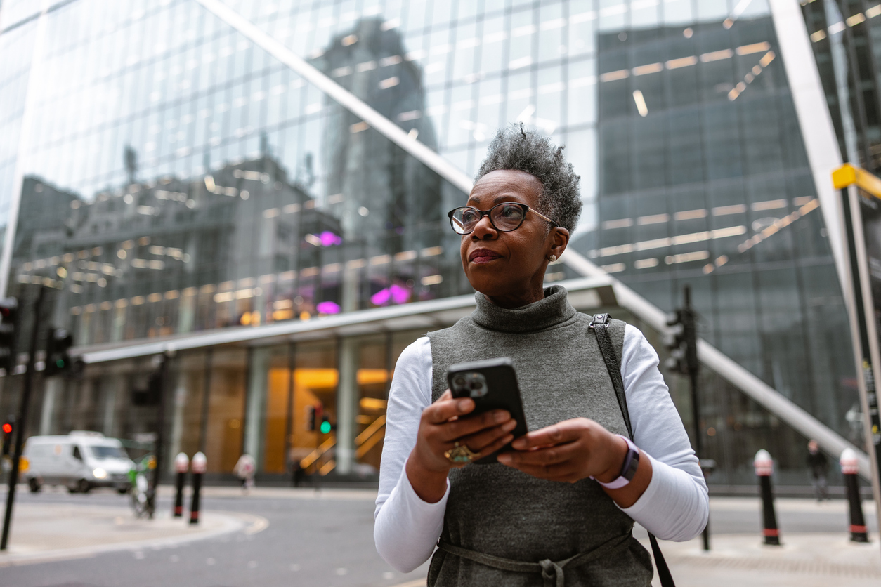 Older woman in a city uses cellphone to navigate