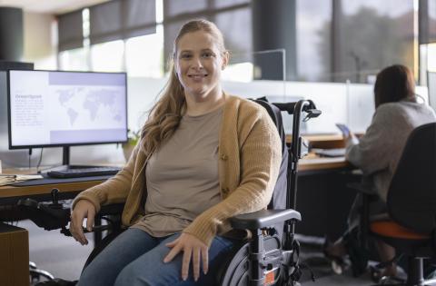 Young woman sits in her wheelchair at her desk at work